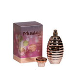 The image shows a perfume product called "Musky Makkaj." It includes the packaging box and the perfume bottle. The bottle has a distinctive metallic pink color with horizontal stripes and a removable cap, which is designed to resemble a decorative crown in gold and black. The box has a purple background with a gradient effect and features artistic representations of plants in gold, pink, and green, along with the text "Musky" in large letters and "Makkaj" in smaller print below.