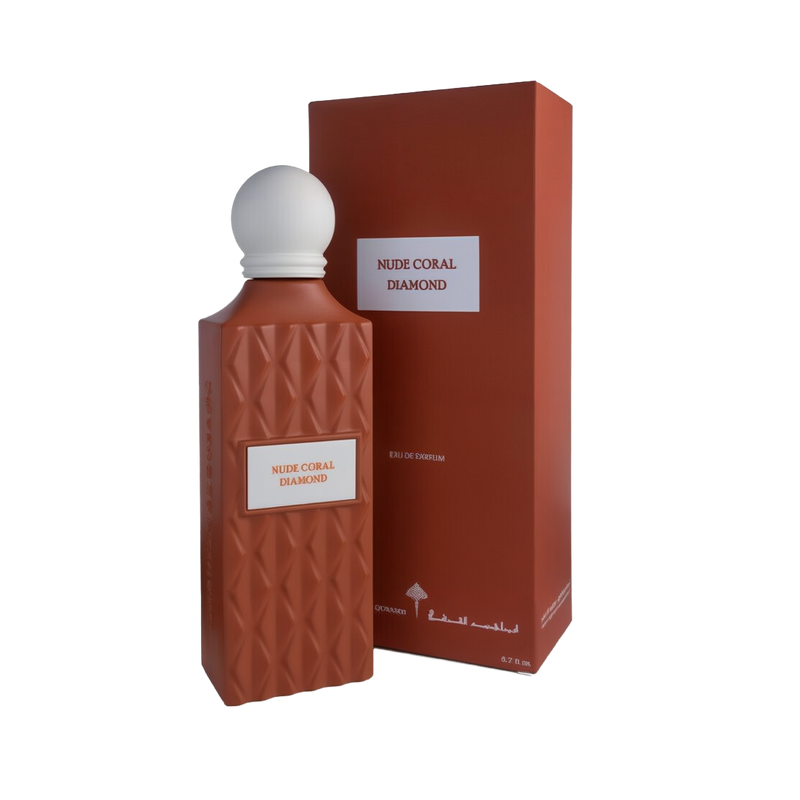 A sophisticated bottle of Nude Coral Diamond Eau e Parfum by Ibraheem Al-Qurashi, displayed next to its matching box. The bottle features a matte, coral-colored geometric texture with a diamond pattern and a white rectangular label that reads 'NUDE CORAL DIAMOND' in red text. It is topped with a smooth, rounded white cap. The packaging mirrors the coral color and minimalist aesthetic, with the same label and white brand markings near the base.