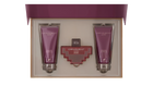 The image shows a gift set by Afnan Perfumes, "ORNAMENT purple allure". It features a perfume bottle and two tubes of shower gel, all in a coordinated deep purple color. The bottle has a unique, cross-shaped design with a red body and silver metalwork. The shower gels are labeled "ENERGIZING SHOWER GEL POUR FEMME" and are housed in sleek, metallic purple tubes.
