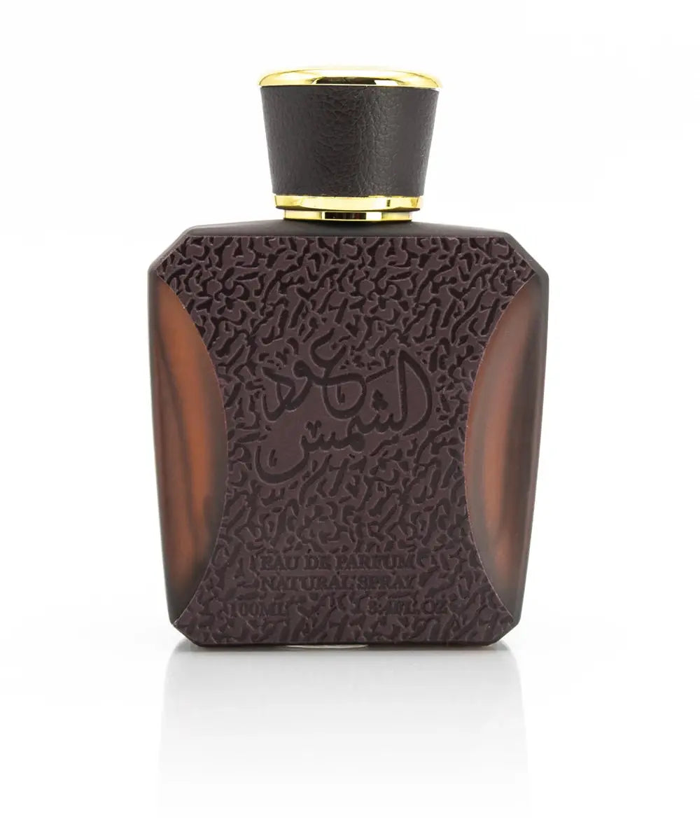  The image features a perfume bottle with a unique design. The bottle appears to be a dark translucent brown with a textured pattern covering its surface, giving it a luxurious feel. The cap of the bottle is black with a gold band around its base. On the front, in relief against the textured pattern, is Arabic script in a matching dark color. Below the script, the words "EAU DE PARFUM NATURAL SPRAY 100ML 3.4 Fl.oz." are written in a clear, legible font.