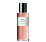 The image shows a slender rectangular perfume bottle with a rosy pink liquid inside, suggesting a feminine and sophisticated fragrance. The bottle has a simple black cap that contrasts with its body. The label is elegantly framed, featuring the name "OUD ISPAHAN" in capital letters, and below in smaller font, "PRIVÉE COUTURE COLLECTION".