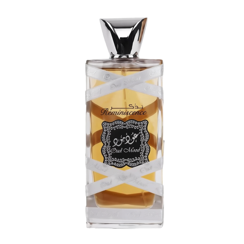 The image displays a perfume bottle with the following attributes:  The bottle is rectangular with a clear glass design, allowing a view of the amber-colored perfume inside. A silver ribbon with the words "Oud Mood" printed in a repeating pattern wraps around the bottle. The central label is ornate with a black background and white decorative border; it features Arabic calligraphy and the word "Reminiscence" in English script.