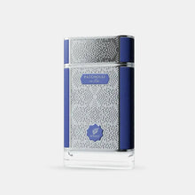 The image displays a perfume bottle with a contemporary design. It has a clear glass body decorated with a white geometric pattern that creates a visually striking texture. A navy blue label with the word "PATCHOULI" in white letters is centered on the bottle, with "on fire" in smaller text below. The brand "AFNAN" is represented by a shield-shaped logo placed below the label.