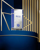 The image features a perfume bottle positioned against an artistic backdrop. The bottle has a clear glass structure with a white geometric pattern and is adorned with a navy blue label that reads "PATCHOULI on fire" with the "AFNAN" logo situated just below in a shield-like emblem.  The lighting accentuates the gold tones and the rich blue hues, adding to the premium presentation of the product.