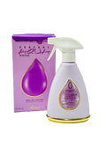 The image displays a room and linen mist spray bottle next to its packaging box. The spray bottle is white with a purple label featuring "KAUSAR" in Arabic and Latin scripts within a teardrop-shaped clear window. The nozzle is white with a purple actuator.  The box is purple with a gold and white teardrop motif, and the text "PERFUME AQUA KAUSAR" and "ROOM AND LINEN MIST 375 ml." The box and the bottle share the same color theme and branding.