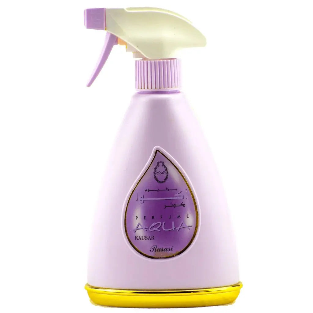 The image shows a light purple spray bottle for "KAUSAR" perfume, which is part of the AQUA series. The bottle features a white spray nozzle with a purple actuator and a distinctive teardrop-shaped transparent window that showcases the name "KAUSAR" in Arabic script and "AQUA" in Latin script. The label inside the window has a purple background, and there's a yellow base that adds a contrasting color accent. The background of the image is white, emphasizing the pastel color and elegant design of the bottle.