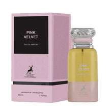 A pink rectangular box labeled ‘Pink Velvet Eau De Parfum’ by Maison Alhambra, displayed beside a tall, cylindrical perfume bottle featuring a metallic swirl cap and a yellow-to-pink color gradient.