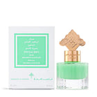  The image depicts a perfume bottle with a vibrant green liquid next to its packaging. The bottle has a clear bottom and is topped with a gold ornate cap featuring intricate designs, possibly inspired by Middle Eastern or Islamic art. The packaging box is white with a green label that reads "PISTACHIO MUSK IBRAHEEM AL QURASHI SPECIAL KHAMRIYA FOR HAIR" in both English and Arabic script. The box also indicates a volume of "15ml / 0.5 fl.oz."