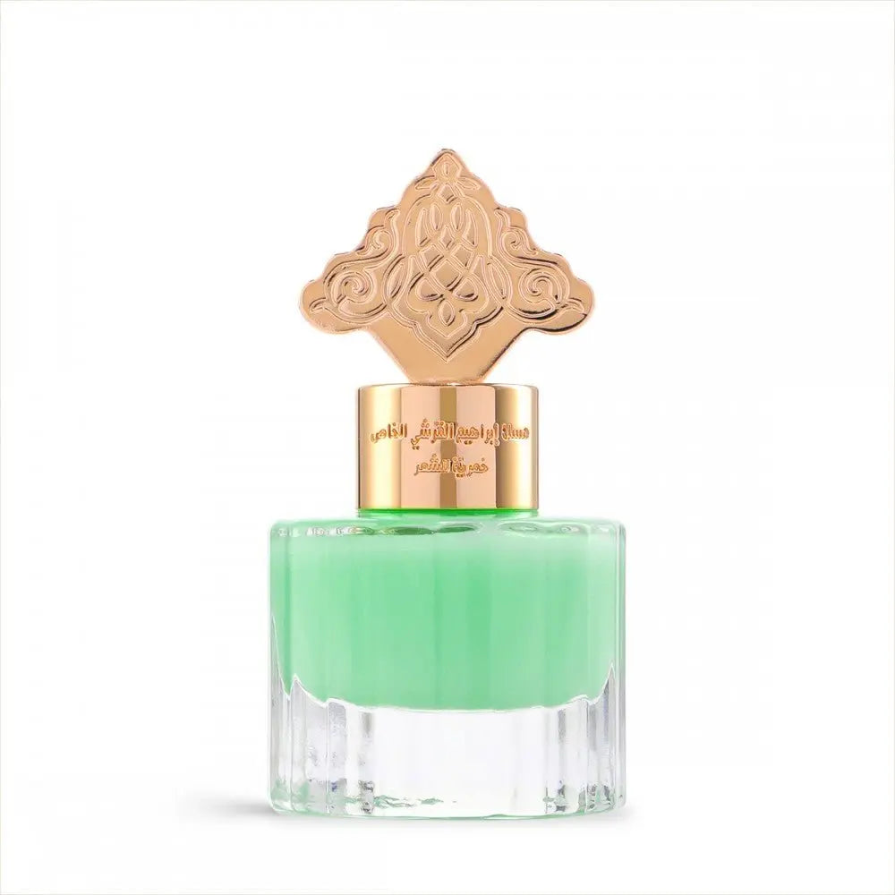 This is an image of a perfume bottle with a clear base and a vibrant green liquid inside. The cap is ornate and gold-colored, featuring an intricate design that suggests an inspiration from Middle Eastern or Islamic art. There is Arabic calligraphy on the gold band around the neck of the bottle, likely indicating the fragrance's name or brand.
