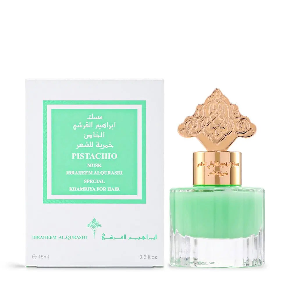  The image depicts a perfume bottle with a vibrant green liquid next to its packaging. The bottle has a clear bottom and is topped with a gold ornate cap featuring intricate designs, possibly inspired by Middle Eastern or Islamic art. The packaging box is white with a green label that reads "PISTACHIO MUSK IBRAHEEM AL QURASHI SPECIAL KHAMRIYA FOR HAIR" in both English and Arabic script. The box also indicates a volume of "15ml / 0.5 fl.oz."