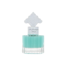 The image features a transparent glass bottle filled with a teal-colored liquid, suggesting a fragrance or scented product. The bottle has a unique, white ornate cap that resembles traditional Middle Eastern pattern.