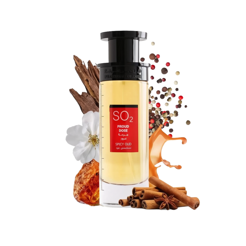 An image of a tall, rectangular perfume bottle with a yellow to amber gradient liquid and a black cap. The label has a prominent red rectangle with the text "SO2 PROUD DOSE SPICY OUD" in both English and Arabic. The product is presented with visual elements that suggest its fragrance notes: white flowers, cinnamon sticks, star anise, amber resin, and a sprinkle of multicolored peppercorns.