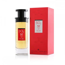 The image presents a tall, cylindrical perfume bottle with a black cap next to its vibrant red packaging box. The bottle's label is red with the text "SO2 PROUD DOSE SPICY OUD" in white, complemented by Arabic script. The transparent bottle reveals a yellow to amber gradient liquid, suggesting a warm scent. The red box features a similar label and chemical compound-like designs in a lighter shade of red.