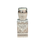 The image shows a product named "Pure Musk Hand and Body Lotion." The lotion is packaged in a light beige container with a clear lid and placed on top of a matching beige box adorned with intricate, elegant silver patterns and Arabic calligraphy. The box prominently features the product name "Pure Musk." The sophisticated packaging suggests a luxurious and high-quality skincare product.