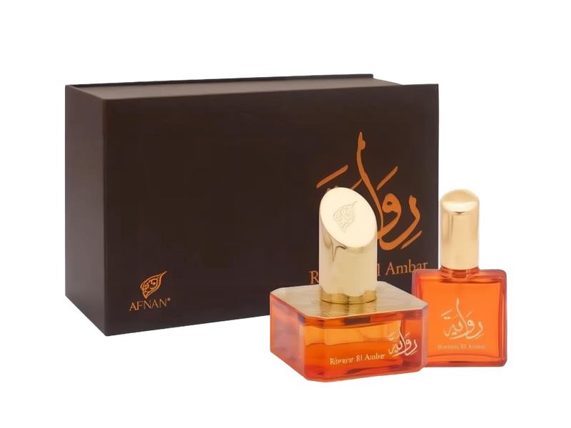 The image shows a set of two perfume bottles with a dark brown backdrop provided by their box packaging. On the left, there is a larger rectangular packaging box with the brand logo "AFNAN" in gold at the lower left corner and an elaborate calligraphic design in gold at the center. The design possibly represents the name of the perfume in Arabic script. In front of the box, there are two transparent orange-colored glass perfume bottles, each with gold caps.