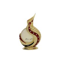 The image shows an intricately designed perfume bottle:  The bottle has a spherical base with a slender, curved neck that extends into a pointed tip, reminiscent of traditional Middle Eastern design. It is predominantly off-white with gold accents and features a decorative red swirl with embedded gem-like stones. Arabic calligraphy is displayed on the lower part of the bottle, adding to its cultural aesthetic. The bottle rests on a small, ornate gold stand.