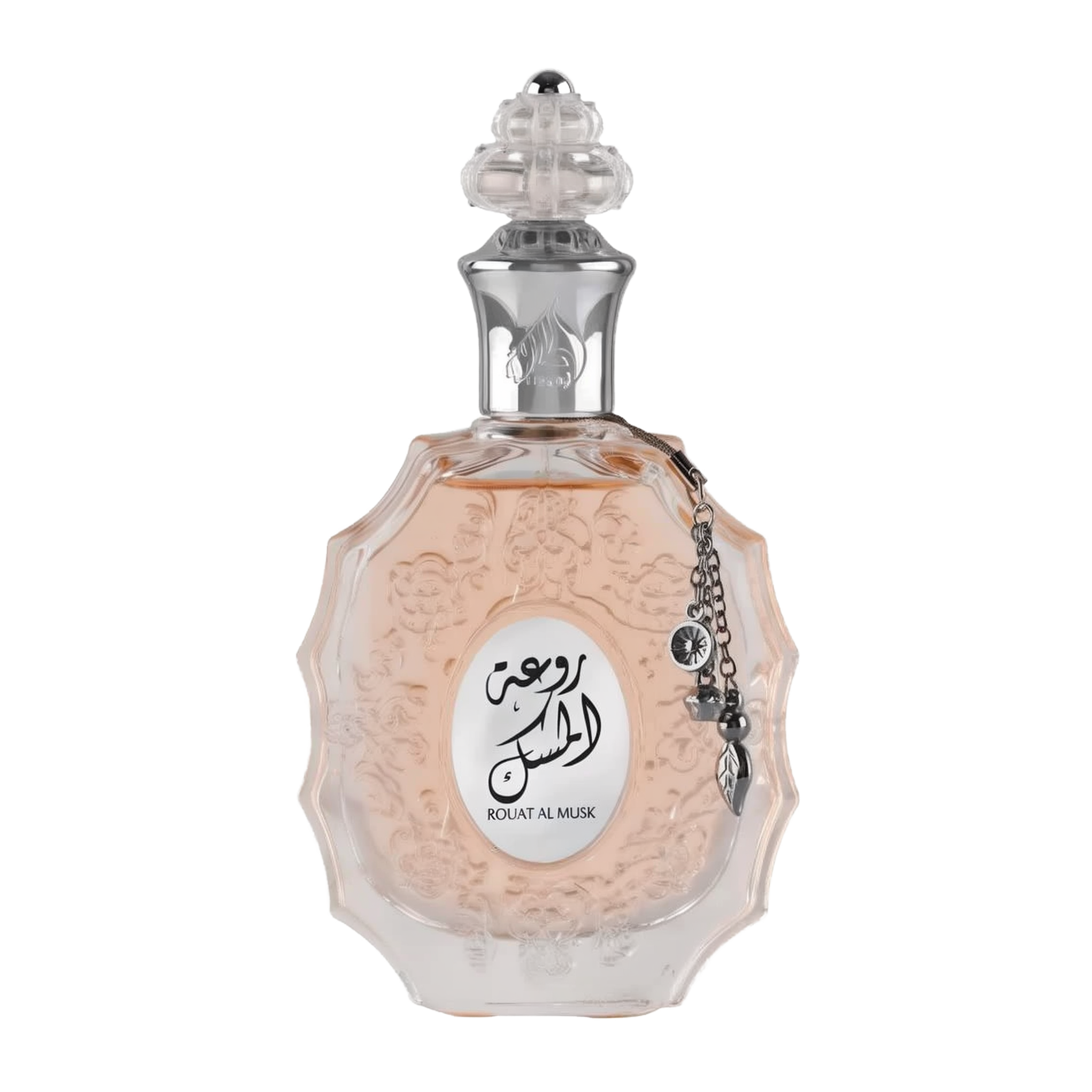 The image shows a decorative perfume bottle:  The bottle has an ornate, multi-faceted glass design with a textured surface and a pale pink tint, suggesting a delicate fragrance within. It features a clear glass stopper with an intricate cut pattern on top. A metallic silver chain with a charm and a small black stone is attached to the neck of the bottle. The front of the bottle displays a white oval label with Arabic calligraphy and the name "ROUAT AL MUSK" in Roman characters below.