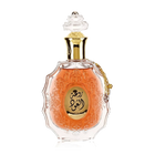 he image features an ornate perfume bottle:  The bottle is made of clear glass with a decorative texture and a central amber-colored panel. A clear and intricate glass stopper tops the bottle. A golden metallic chain with a charm is attached to the neck of the bottle. Arabic calligraphy is featured within the amber panel, and the name "ROUAT AL OUD" is inscribed in English below the calligraphy.