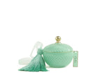 A round, Art Deco-style candle container in a tiffany blue color with a textured diamond pattern. The container has a gold-colored knob on the lid and a matching tiffany blue tassel attached to a tag that reads 'Côte Noire.' The candle is set against a plain white background.