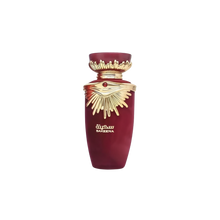 The image shows a perfume bottle from the brand Lattafa, specifically the "SAKEENA" fragrance. The bottle is maroon with a tapered shape and features a golden, ornate lid that resembles a crown, complete with a gemstone accent in the center. The design elements suggest a luxurious and exotic scent. "SAKEENA" is written in gold Arabic calligraphy on the body of the bottle, which is set against a plain background, emphasizing the bottle's elegant design and rich color palette.
