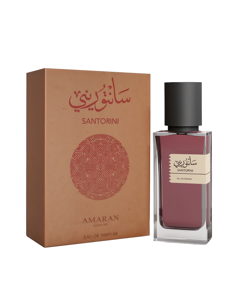 A rectangular glass perfume bottle with burgundy liquid and a black cap, labeled ‘Santorini’ by Amaran Parfums, stands next to a tan box featuring red Arabic script and a circular geometric design.