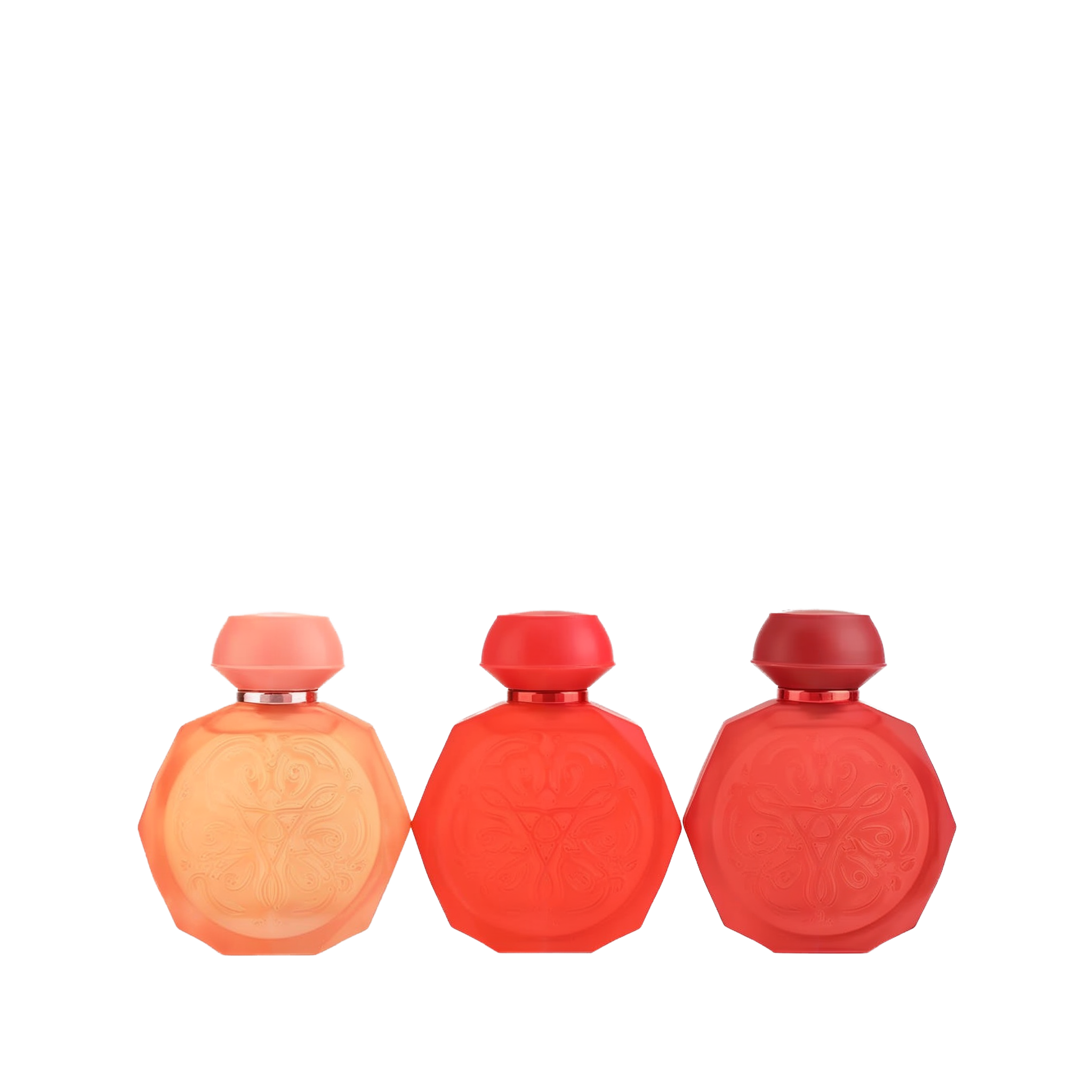 A set of three Gissah perfume bottles in a range of red hues, each with an octagonal shape and intricate embossed designs on the front. The bottles feature smooth, matching caps and come in shades of peach, vibrant red, and deep red. The elegant and minimalist design highlights the gradient of colors, making the set visually appealing and sophisticated.