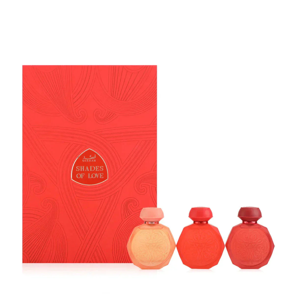 A set of three Gissah perfume bottles in varying shades of red, displayed in front of a red box labeled "Shades of Love." The bottles are octagonal with intricate embossed designs and smooth caps, and they come in peach, vibrant red, and deep red hues. The box features elegant patterns and the Gissah brand name, complementing the theme of love and passion conveyed by the colors and design of the bottles.