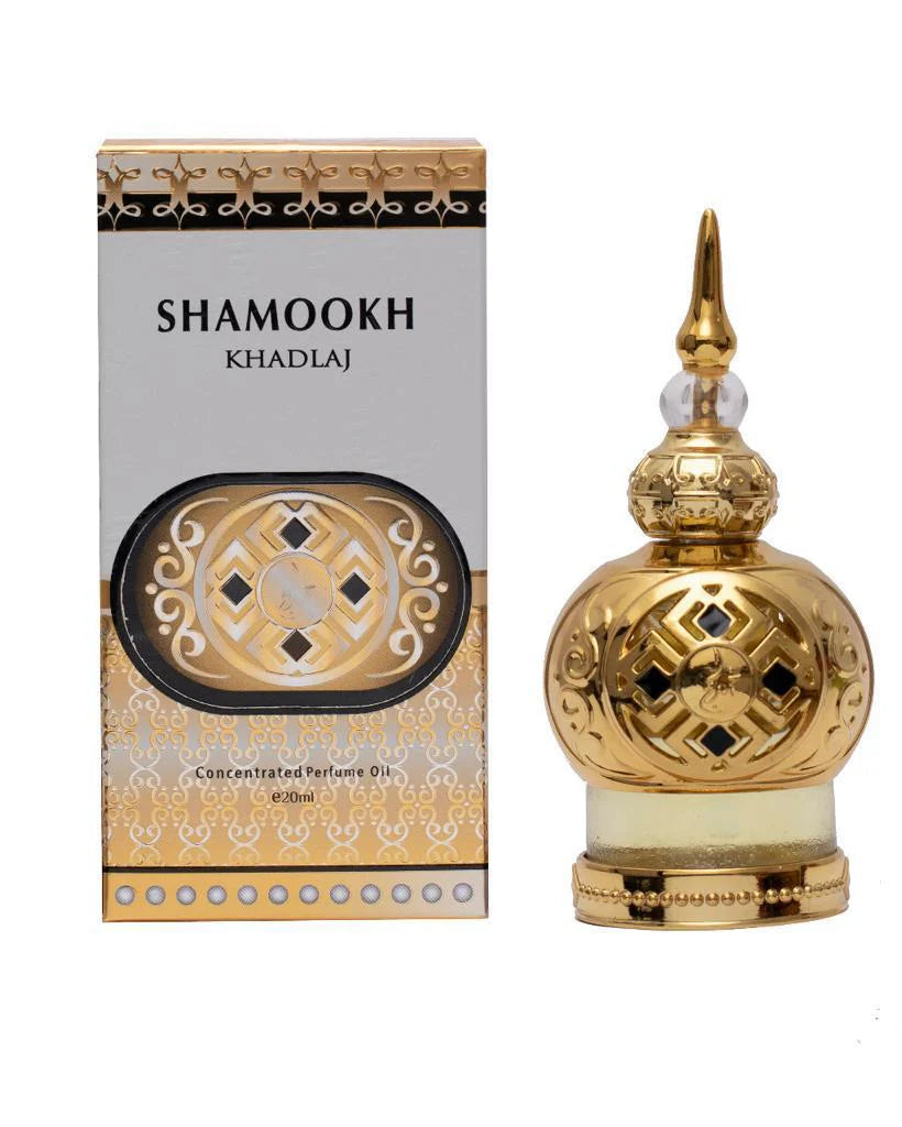 The image shows a product called "Shamookh" by Khadlaj, which is a concentrated perfume oil. The product is presented in an ornate 20ml bottle with a spherical design. The bottle is gold with intricate patterns and a decorative, pointed cap, giving it a luxurious and elegant appearance. The packaging box complements the bottle's design with a gold and black theme, featuring the product name "Shamookh" in bold letters.