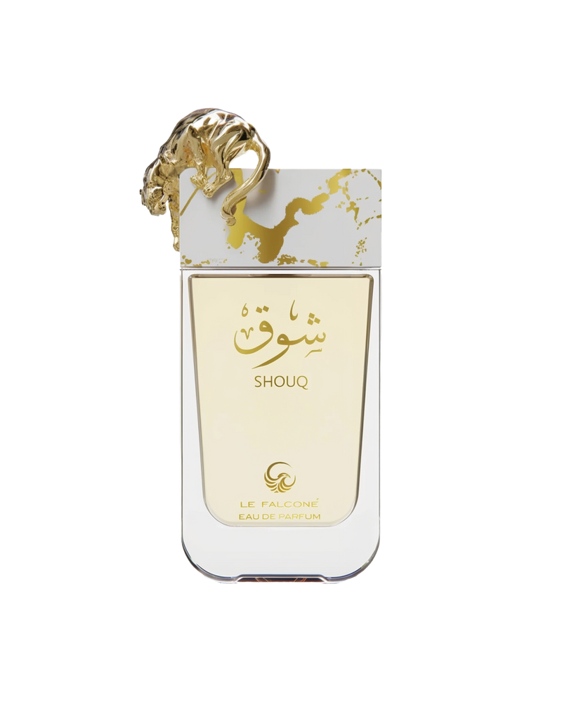 A rectangular, clear glass perfume bottle with pale gold liquid, featuring Arabic calligraphy and the word ‘Shouq’ in gold, topped by a sculpted gold big cat, and labeled ‘Le Falcone Eau De Parfum’ at the bottom.