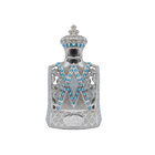 The image depicts a highly ornate perfume bottle with a design that mimics the aesthetic of royal regalia. The bottle is predominantly silver with intricate filigree work and is adorned with a pattern of bright blue gemstones arranged in V-shaped lines along the front. The neck and shoulder of the bottle are also embellished with blue gems and delicate silver patterns, leading up to a crowned cap that features similar gemstones and a studded pattern.