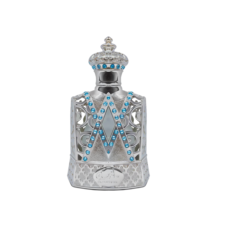 The image depicts a highly ornate perfume bottle with a design that mimics the aesthetic of royal regalia. The bottle is predominantly silver with intricate filigree work and is adorned with a pattern of bright blue gemstones arranged in V-shaped lines along the front. The neck and shoulder of the bottle are also embellished with blue gems and delicate silver patterns, leading up to a crowned cap that features similar gemstones and a studded pattern.