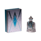 The image displays a perfume bottle next to its packaging. The packaging is a tall rectangular box with a silver color scheme and features a pattern that mimics the design of the bottle, with a central V-shaped motif outlined in blue. The bottle itself is crafted with intricate silver detailing, resembling a piece of filigree work, and is adorned with bright blue gemstones arranged in two parallel V-shaped lines that accentuate the bottle's design. 