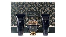 The image features a luxurious bath and body set from the "SOUVENIR Desert Rose" collection by Afnan. The set includes a spherical golden perfume bottle with a clear dome top, flanked by two navy blue tubes—one labeled as "ENERGIZING SHOWER GEL" and the other as "LUSTEROUS NATURAL BODY LOTION". Each product has gold lettering and rose accents. The background and base of the set feature an elegant pattern of gold roses on a dark, forest green backdrop.