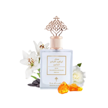 A bottle of 'Special Musk' by Ibraheem Al Qurashi, with a sophisticated design. The perfume bottle is square with a soft blue color and a rose gold ornate cap that features an intricate lattice design. The label has Arabic calligraphy and English text. It is presented with a backdrop of white flowers, possibly lilies, and a white rose, along with two amber-colored resin pieces in front, suggesting a luxurious and aromatic product.