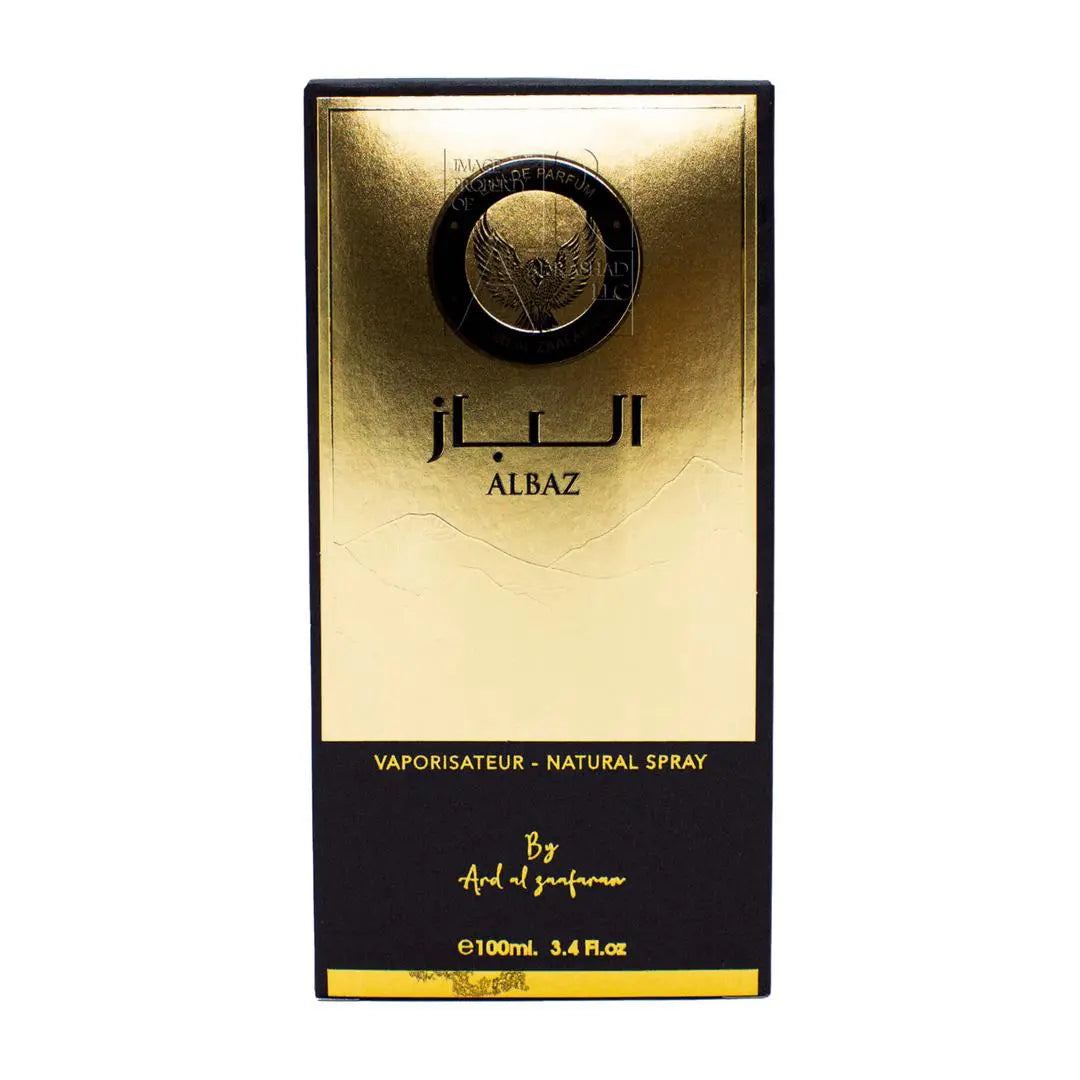 The image displays the packaging for a perfume product:  The box is primarily gold with a gradient effect that darkens towards the bottom. At the top, there's a prominent embossed seal in black and gold featuring an eagle design. The name "ALBAZ" is written in large, black Arabic script in the center, with the transliteration below it in smaller black letters. The bottom section of the box is black with gold lettering stating "VAPORISATEUR - NATURAL SPRAY" and "By Ard Al Zaafaran."