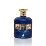The bottle is a deep cobalt blue with a smooth, rounded shape. It has a metallic gold label with the name "AMBERLEY" embossed in the center. Below the main label, in elegant script, is the name "Ombre Blue." A small, gold stag emblem is placed at the bottom center of the bottle, indicating the logo for "MAISON ALHAMBRA." The cap of the bottle is gold with a textured design, resembling a crown or cog. 