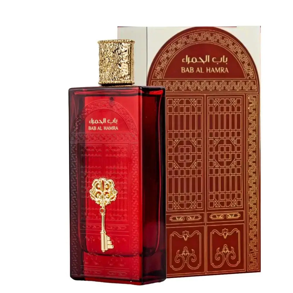 The image features a rectangular perfume bottle with a deep red hue and a highly ornate gold cap. On the bottle is an embossed golden emblem in the shape of a key, which adds to the luxurious appearance of the product. Accompanying the bottle is a box with Arabic and English text, "باب الحمرا / BAB AL HAMRA," likely the name of the fragrance.  The product appears to be of Middle Eastern origin and suggests a fragrance with a rich and exotic scent.