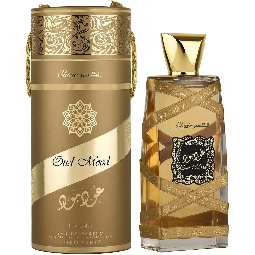 The image shows a perfume bottle and its cylindrical container with a harmonious design:  The perfume bottle is clear with a golden tint, filled with a liquid of a similar hue, indicating the presence of the perfume. Wrapped around the bottle are black ribbons with the name "Oud Mood" printed in a repeating gold pattern. The center of the bottle features a decorative white label with a detailed black border and Arabic calligraphy in the center. 