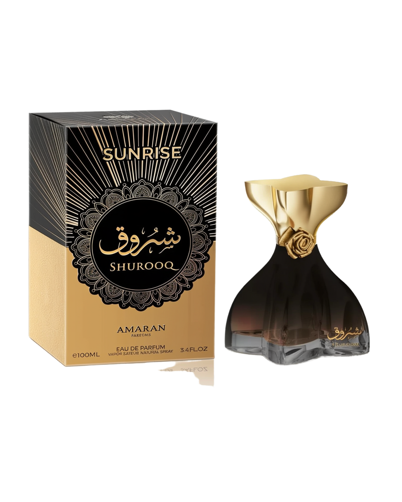 A dark-toned, sculpted perfume bottle with a gold bow-like cap featuring a rose detail, labeled “Sunrise Shurooq” by Amaran, shown beside a matching black and gold box indicating 100ml Eau De Parfum.