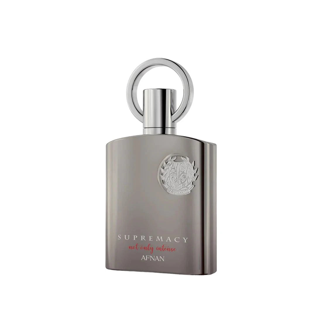 The image features a perfume bottle with a contemporary design named "SUPREMACY not only intense" by Afnan. The bottle has a matte silver-gray finish with a sturdy, rectangular shape and slightly rounded edges. The cap is a simple yet elegant silver ring that stands vertically on top of the bottle. An intricate emblem is embossed on the front, giving the bottle a luxurious and stylish appearance.