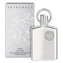 The image shows a product set from "AFNAN" featuring the "SUPREMACY" fragrance for men. On the left is the perfume's packaging box, which is a light grey with a subtle floral and vine embossed pattern, and the brand and product name printed in silver, reflective lettering. 