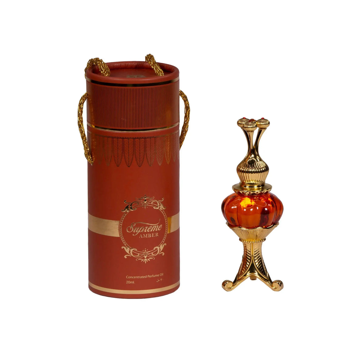 The image features an ornate perfume oil set, consisting of a cylindrical red container with gold trim and decorative elements, and a luxurious golden and red glass perfume oil bottle with an intricate metallic design. The container has a lid with two golden, braided rope-like handles and displays the text "Supreme AMBER" in a decorative golden font, with a smaller inscription "Concentrated Perfume Oil 20ml" below. 