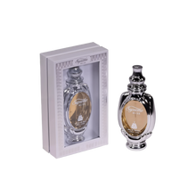 An image of Supreme Musk Eau de Parfum, showing the perfume bottle outside its packaging. The bottle has a traditional and ornate design, with a shiny black exterior and intricate silver accents. The label features the name "Supreme Musk" in elegant script. The packaging is a simple yet classy grey box with a window that allows the bottle to be viewed, bordered with ornamental patterns.