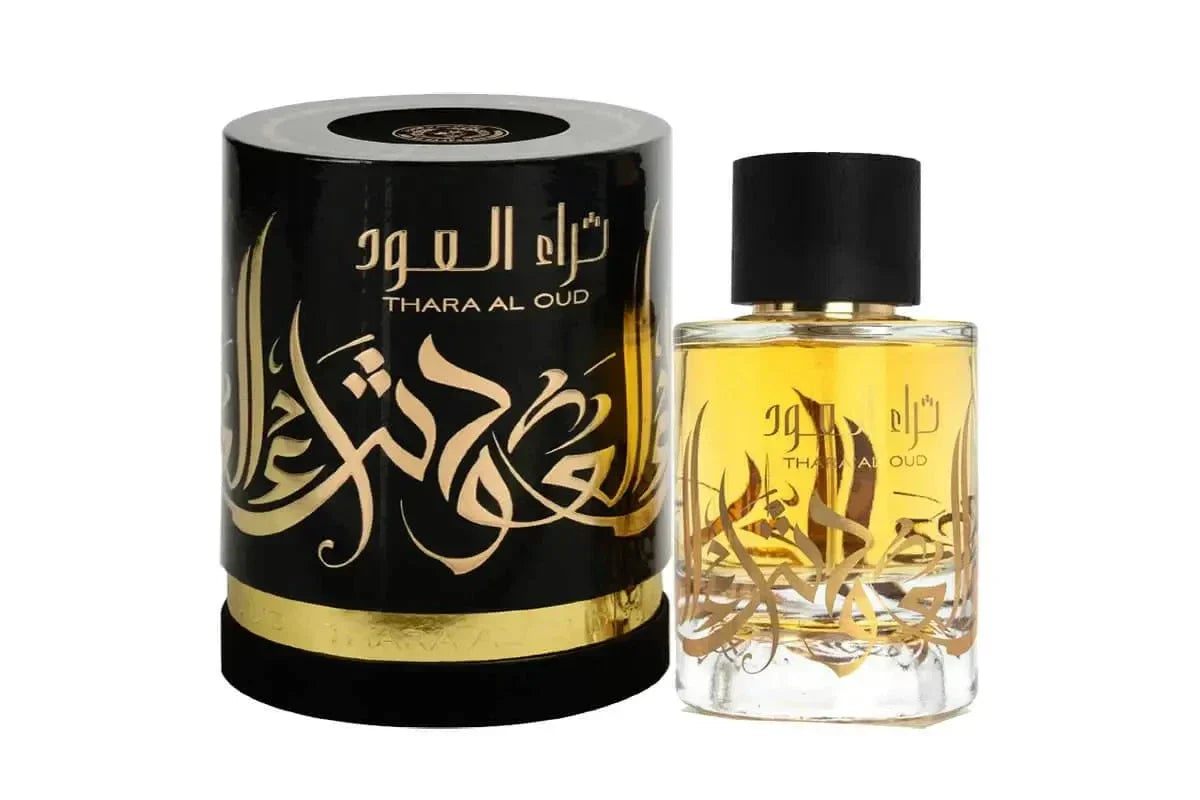 A clear glass perfume bottle with a yellow-amber liquid, featuring a black cap and a gold label with Arabic calligraphy reading "THARA AL OUD." The cylindrical black packaging next to it mirrors the design with the same gold Arabic calligraphy and a decorative gold band around the base. The packaging has a glossy finish with a circular emblem on the top. 