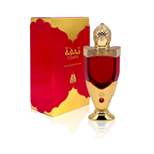 The image shows a luxurious perfume bottle next to its packaging. The bottle has a rich red color with a golden cap, detailed with intricate patterns and topped with a clear faceted finial that resembles a gem. The base and neck of the bottle also feature golden accents. A red gem is embedded in the golden section of the bottle. The packaging box is red with a golden border and carries the brand name "TOHFA" in gold lettering.