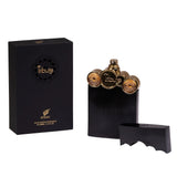 The image showcases a perfume set from "AFNAN" which includes the product packaging and the bottle with its cap removed. The packaging is a sleek black box with the name "Tribute" encircled in an ornamental design and the brand logo in gold lettering. The perfume bottle features a ribbed black exterior with a unique top that includes the cap, which has been removed and placed beside the bottle, mirrors the golden details of the bottle's top.