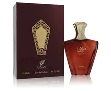 The image shows a perfume bottle next to its packaging. The box is a deep maroon with a golden geometric pattern resembling a lattice design around a central crest, and below this is the brand name "AFNAN" in gold lettering. At the bottom of the bottle, the word "AFNAN" is also visible in gold lettering. The background is white, highlighting the product, and the reflection on the surface suggests that the product is placed on a glass or glossy surface. 
