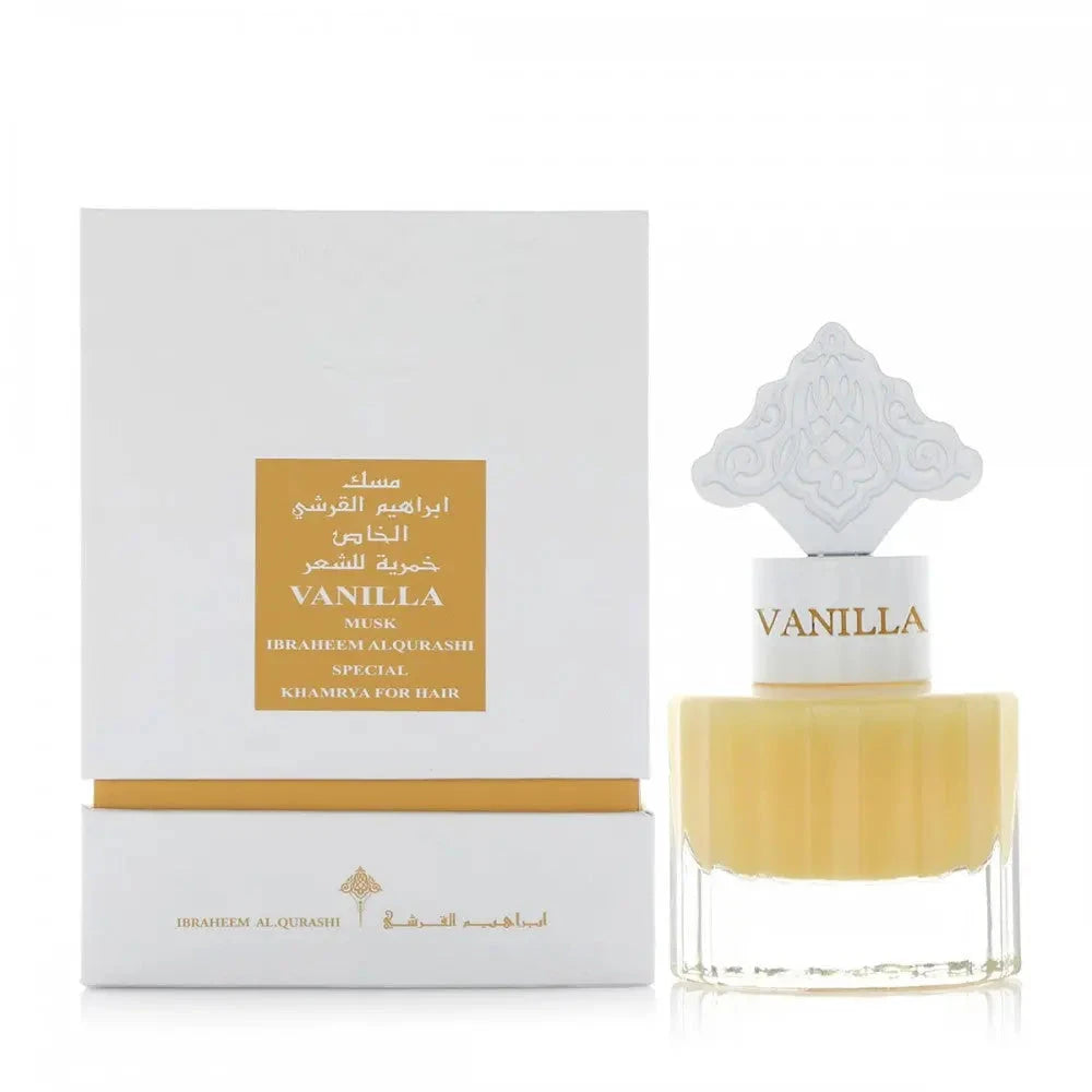 The image shows a perfume or hair mist product set with a bottle and its packaging box. The bottle has a clear bottom filled with a yellow-colored liquid and a white cap labeled "VANILLA" in a font that matches the liquid's color. An ornate white design sits atop the cap, adding a decorative touch. The white box behind the bottle features a gold-colored label with "VANILLA MUSK IBRAHEEM AL.QURASHI SPECIAL KHAMRIYA FOR HAIR" in both English and Arabic, and a gold band at the bottom.