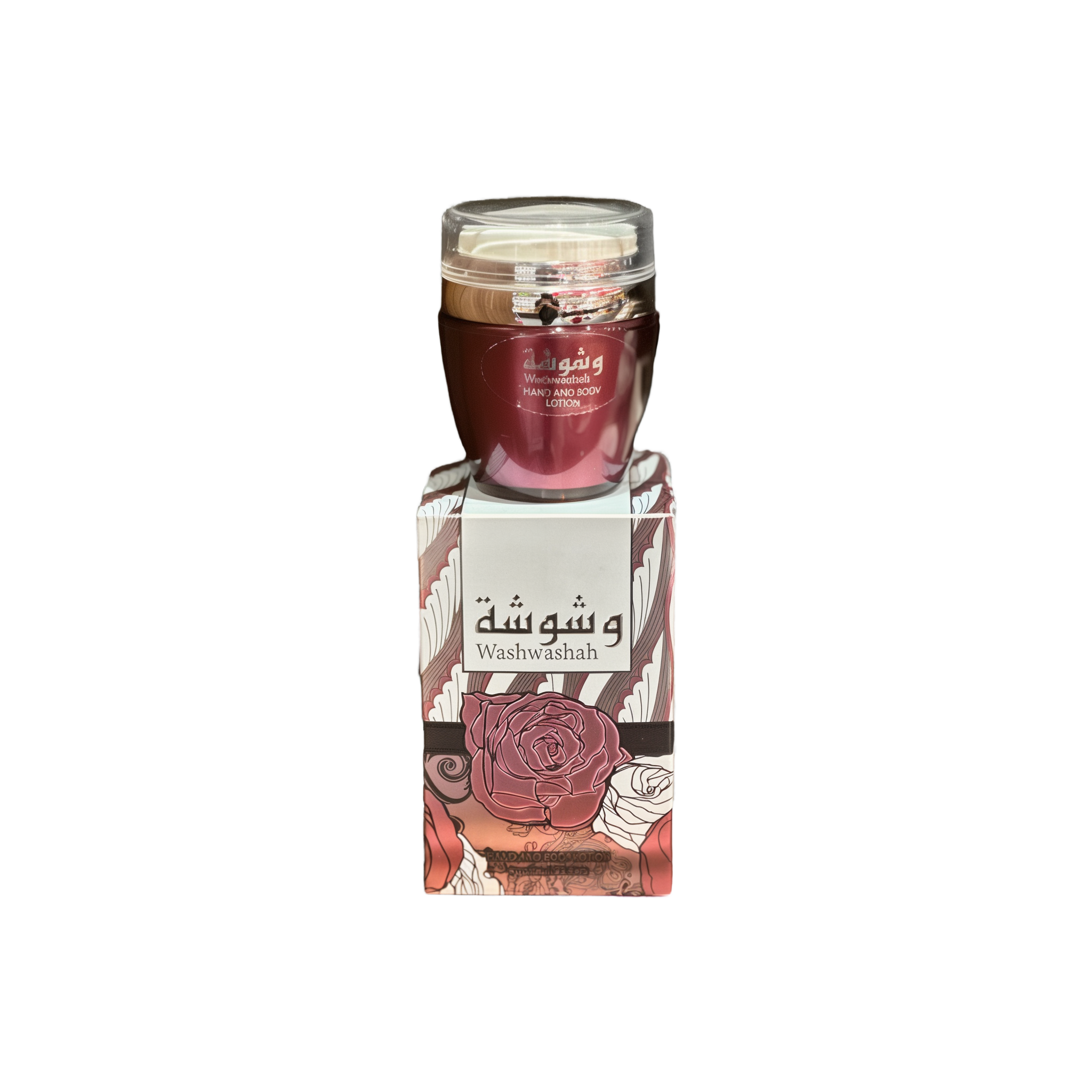 The image shows a product named "Washwashah Hand and Body Lotion." The lotion comes in a dark red container with a clear lid and is placed on top of a matching red and beige box adorned with intricate floral patterns and Arabic calligraphy. The box prominently features the product name "Washwashah" along with an illustration of a rose. The elegant and artistic packaging suggests a luxurious and high-quality skincare product.