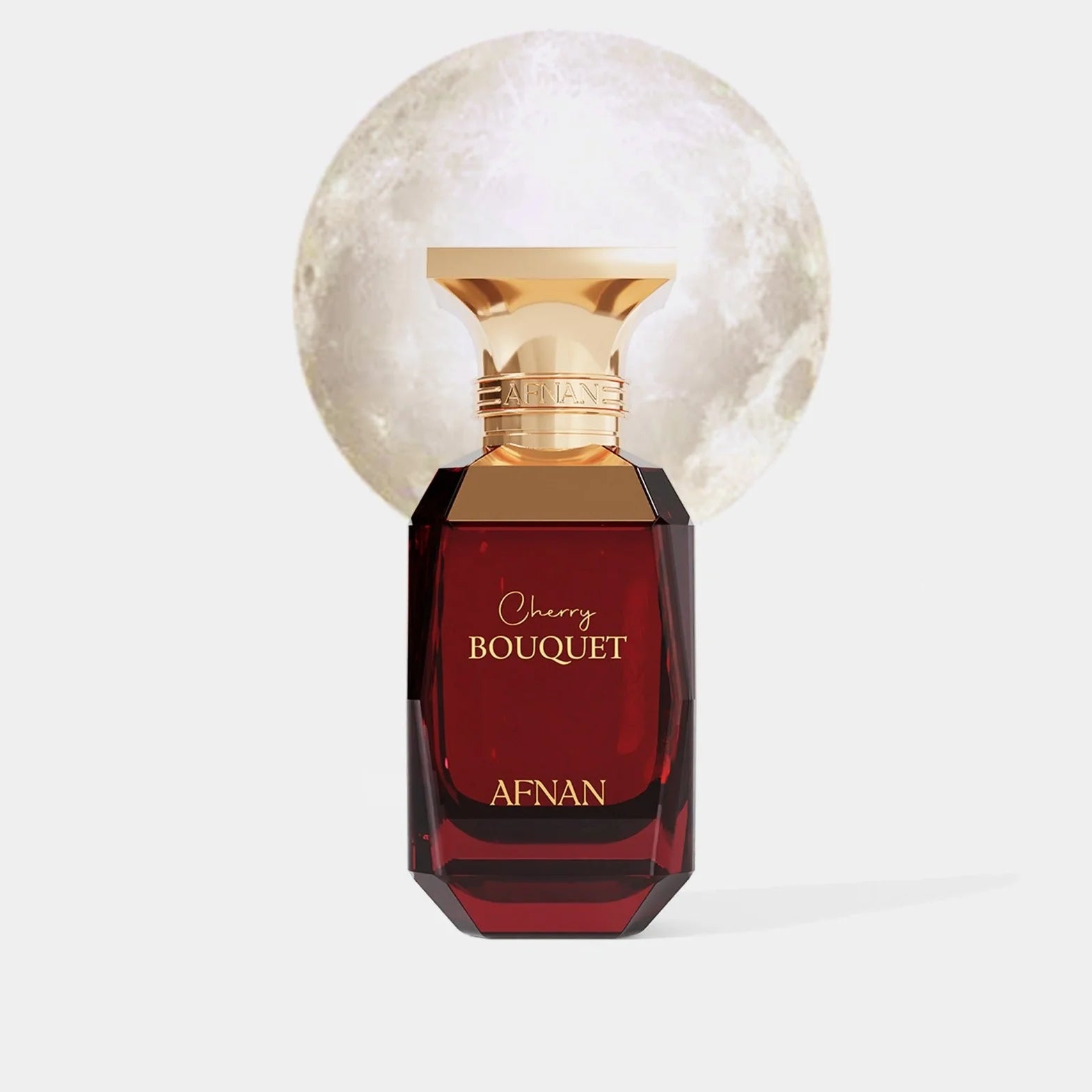 The image shows a perfume bottle named "Cherry Bouquet" by Afnan, set against a backdrop featuring a large, illuminated full moon. The bottle has a dark red, faceted design that resembles a gemstone, with a luxurious gold-toned cap. The text "Cherry Bouquet" is written in elegant script on the front of the bottle, and the brand name "Afnan" is displayed in capital letters near the bottom. The combination of the rich red bottle and the bright moon creates a striking and dramatic visual effect.